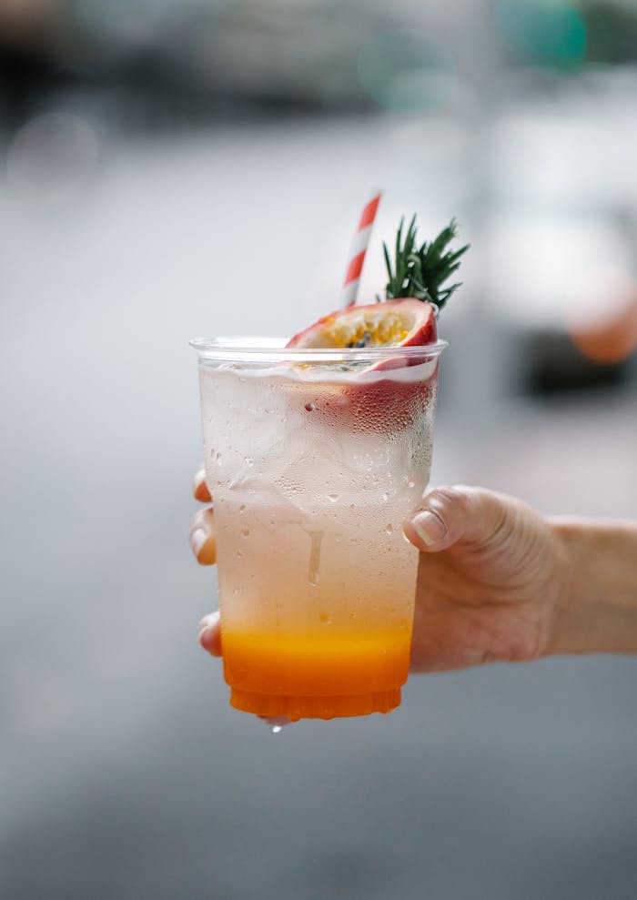 Crafting Captivating Headlines: Your awesome post title goes here Hand holding a refreshing tropical cold drink with passion fruit garnish.